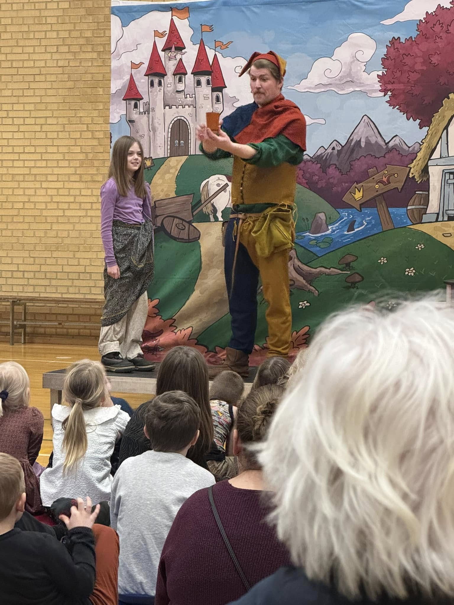 Gøgleren fra Sherwood på scenen i en gymnastiksal sammen med en elev